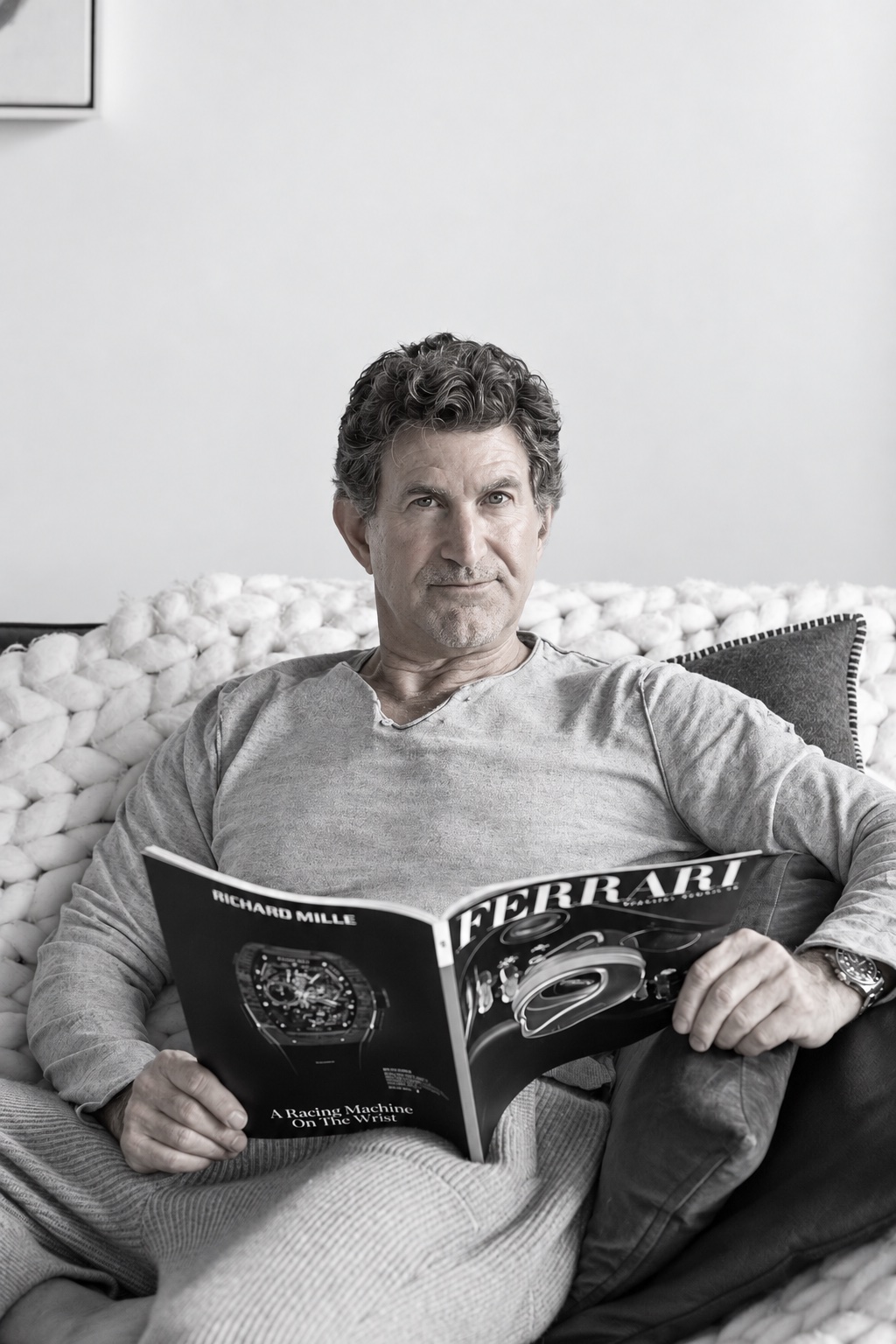Dr. Michael J. Hall seated on a couch reading a magazine